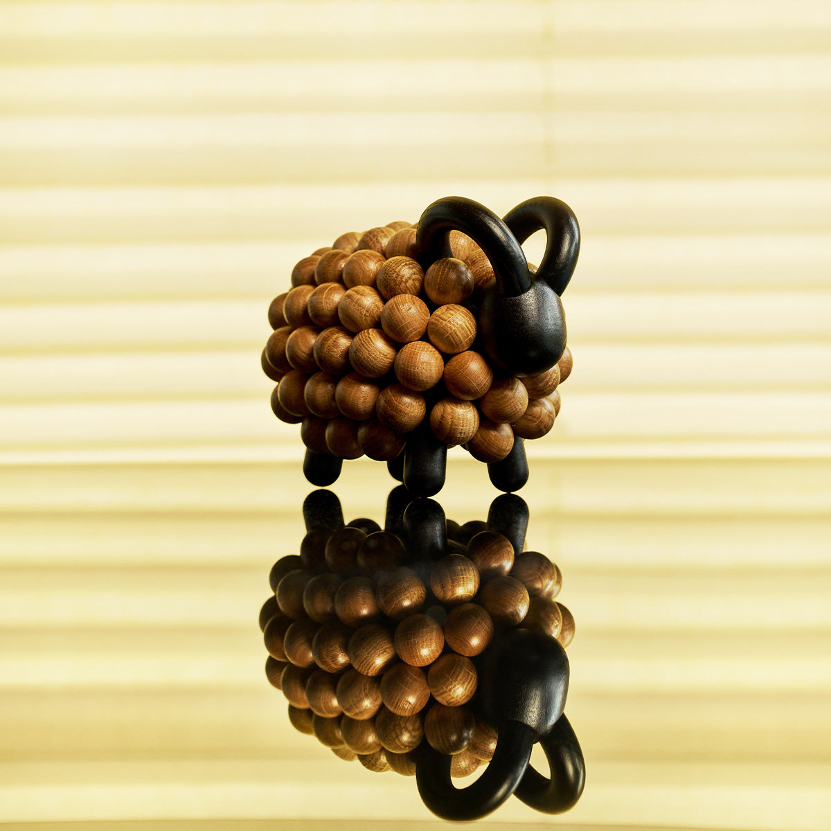 Aarikka's ram shown against a softly lit beige window-blind background with a reflection below.